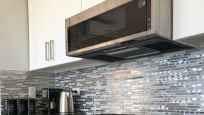 A kitchen with a stainless steel range hood, a microwave, and a coffee maker.