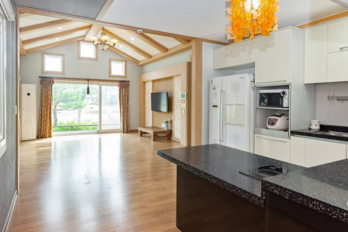 A spacious kitchen with modern appliances, a large island, and a view to the outdoors.
