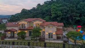 A multi-story residential building with a tiled roof, multiple balconies, and a well-maintained garden. - Gyeongju Woorinuri Pension (Gyeongju)
