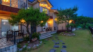 A two-story house with a stone pathway leading to the entrance, surrounded by greenery and a well-maintained lawn. - Gyeongju Woorinuri Pension (Gyeongju)