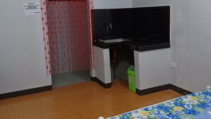 Quarto pequeno com uma cama, uma escrivaninha e uma cortina vermelha com corações.