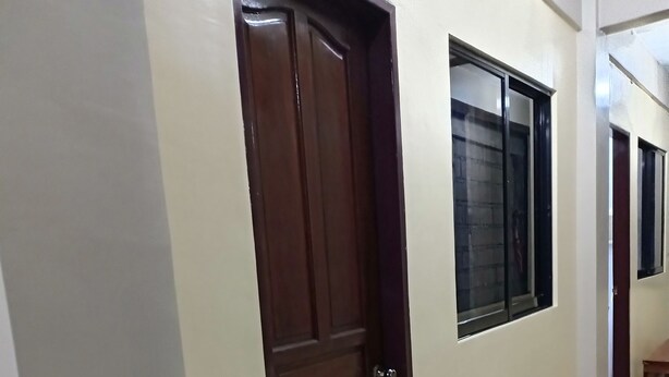 Um corredor com porta de madeira, um banco e janelas.