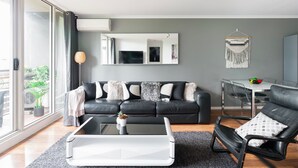 A modern living room with a black leather sofa, a glass coffee table, and a dining area with a table and chairs. - Southbank Boulevard Melbourne (Southbank)