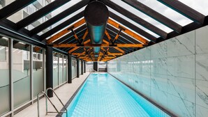 A long indoor swimming pool with a tiled floor and a high ceiling with wooden beams. - Southbank Boulevard Melbourne (Southbank)