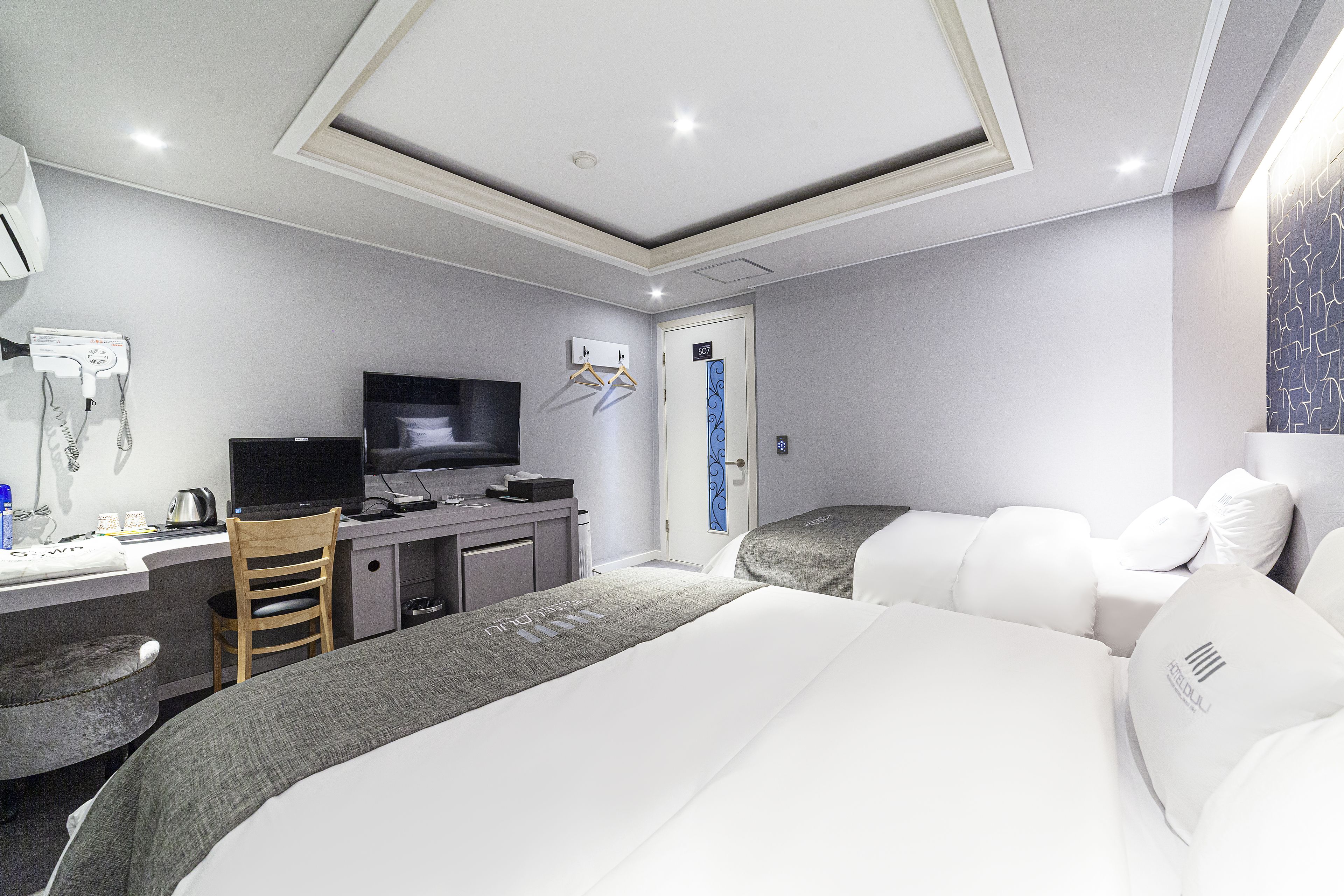 A modern hotel room with a bed, desk, and TV.