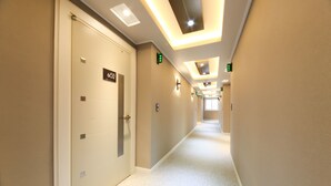 A hotel corridor with a carpeted floor, beige walls, and illuminated ceiling panels. - Business Hotel Duu (Gwangju)