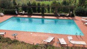 Une piscine rectangulaire à l’eau d’un bleu cristallin, entourée d’une terrasse carrelée agrémentée de chaises longues et de tables.