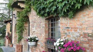 Un bâtiment en briques, dont les murs sont recouverts de lierre, avec un balcon et des jardinières au niveau du rez-de-chaussée.