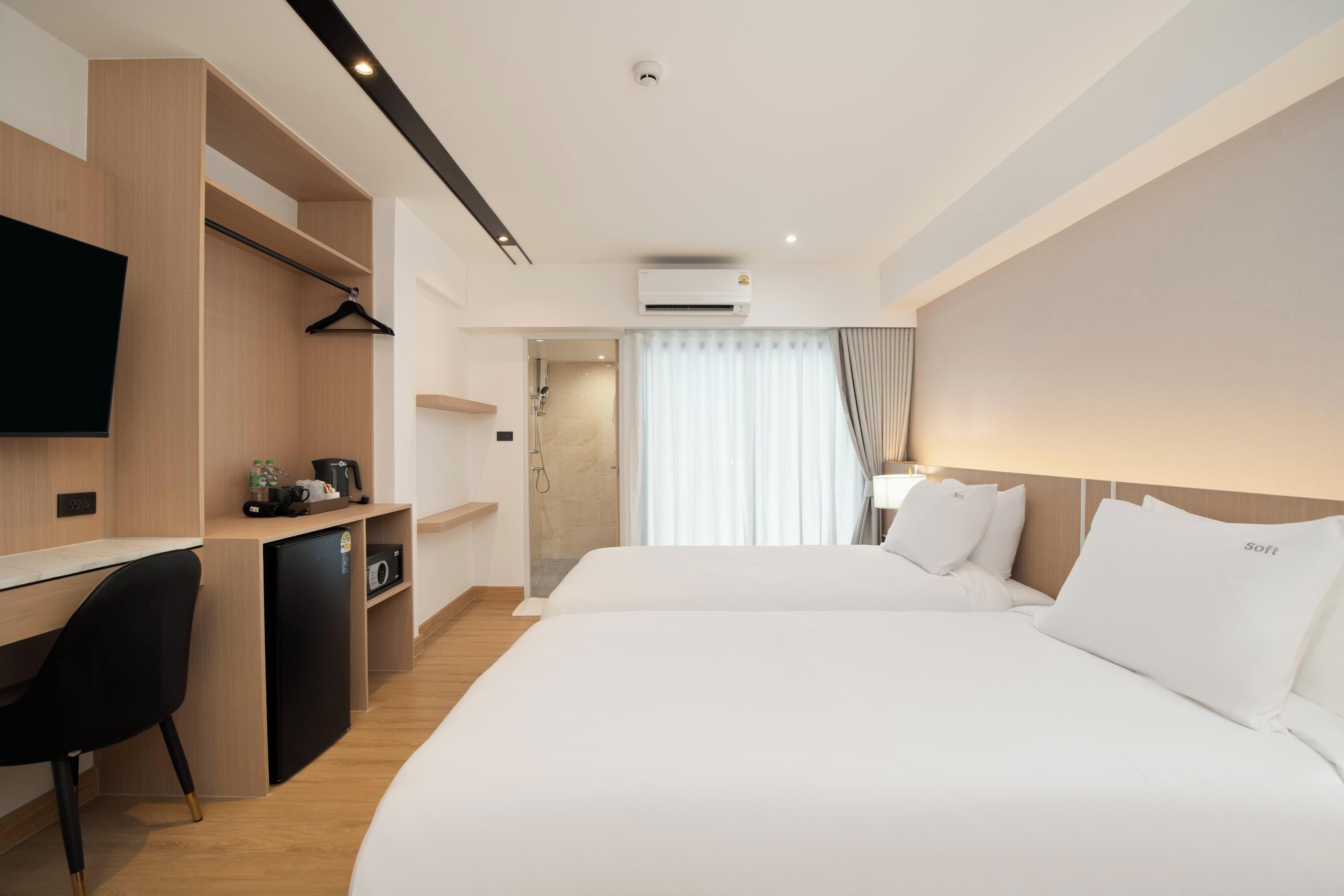 Una habitación de hotel moderna con una cama grande, un escritorio con una silla, un televisor y un equipo de aire acondicionado.