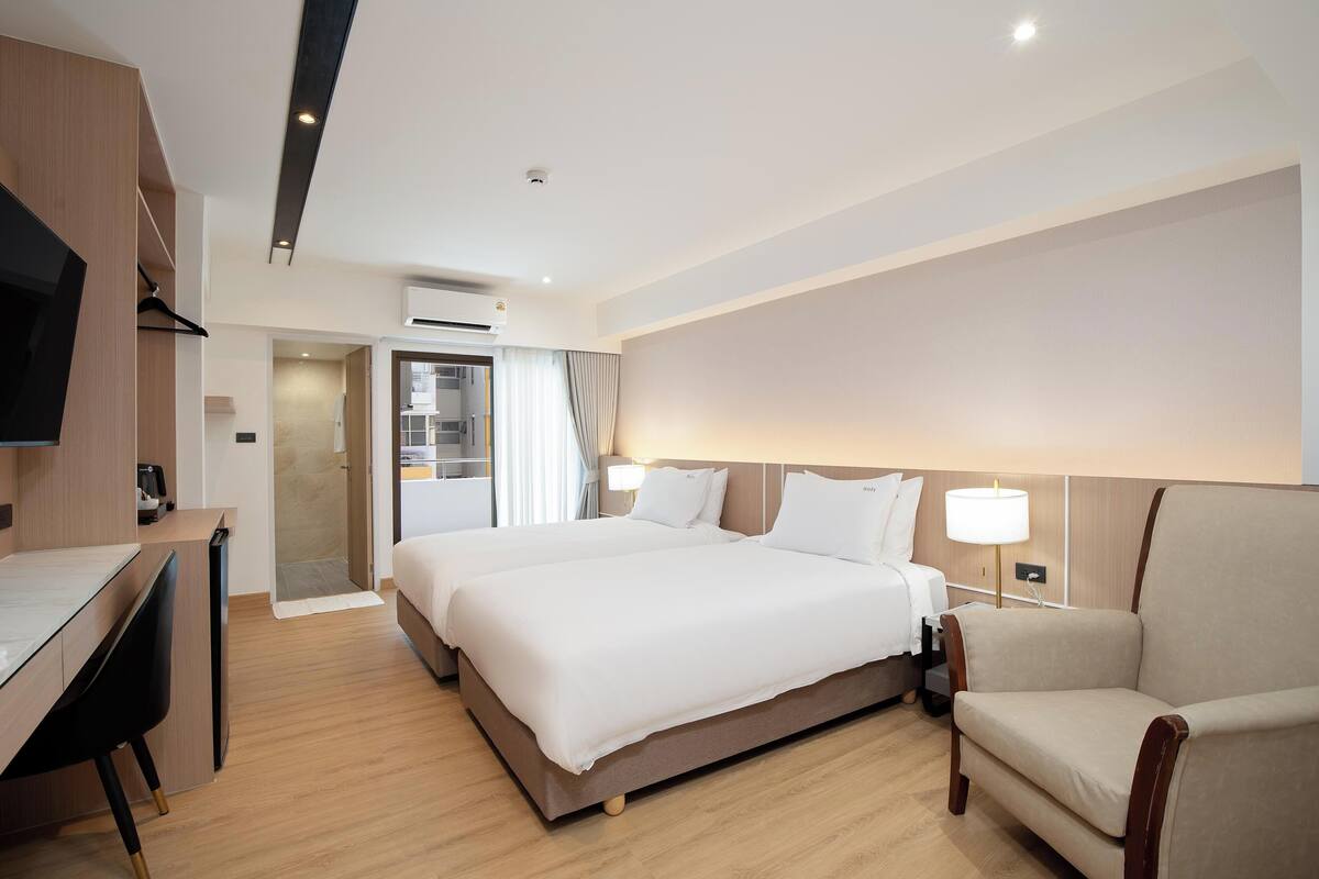Ein Hotelzimmer mit Bett, Schreibtisch, Stuhl und Fernseher.