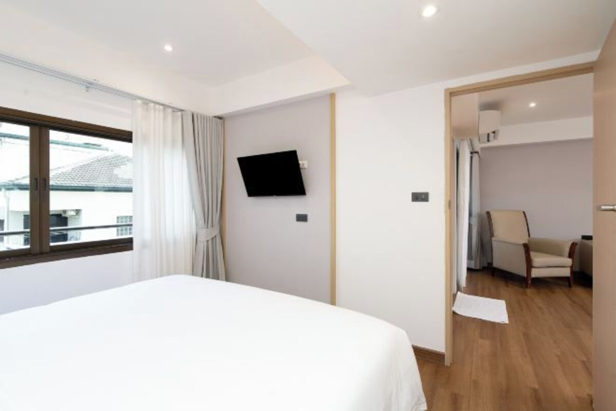 Hotelkamer met een bed, een aan de muur bevestigde televisie, een stoel en uitzicht buiten.