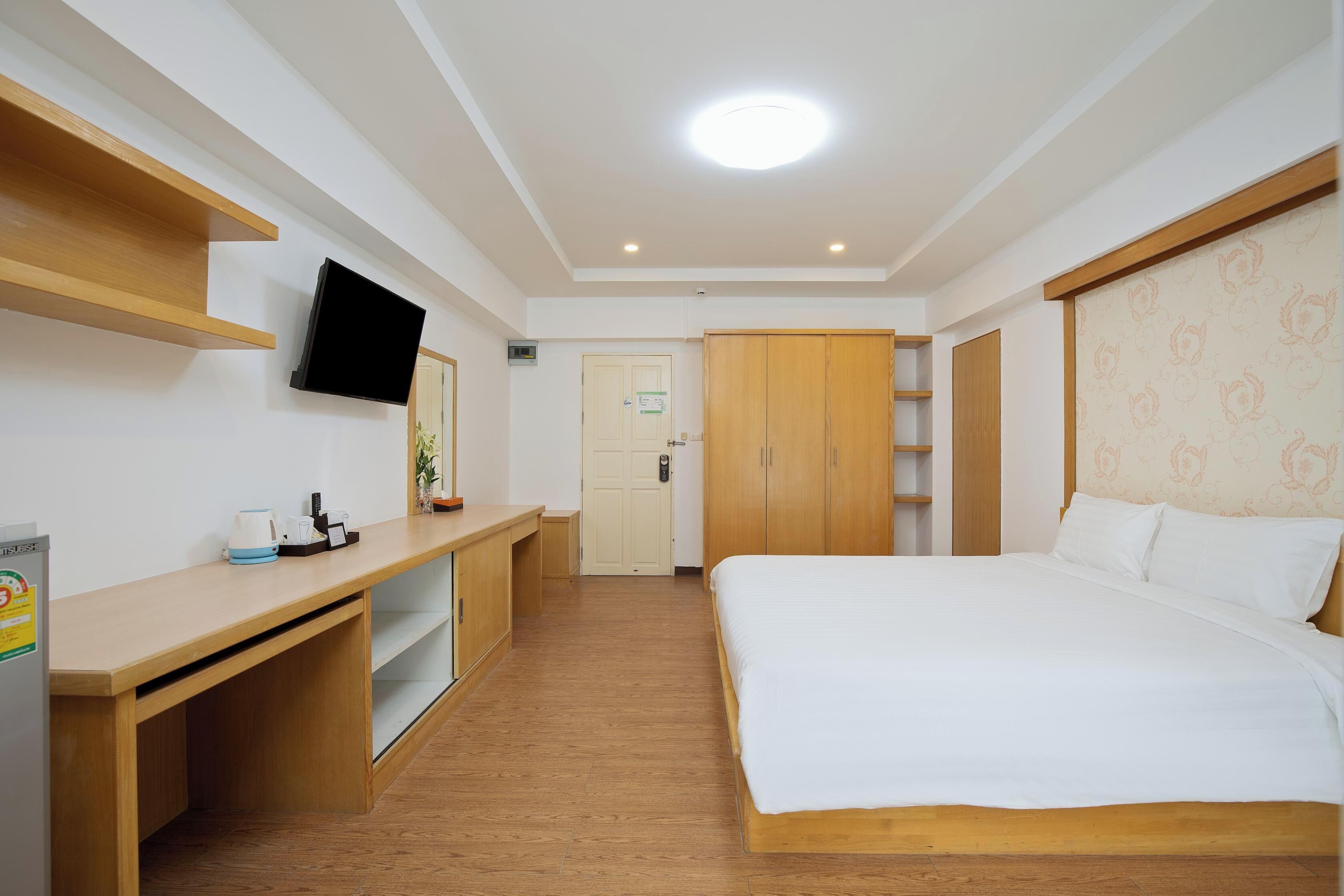 A hotel room with a bed, a desk, a television, and a wardrobe.