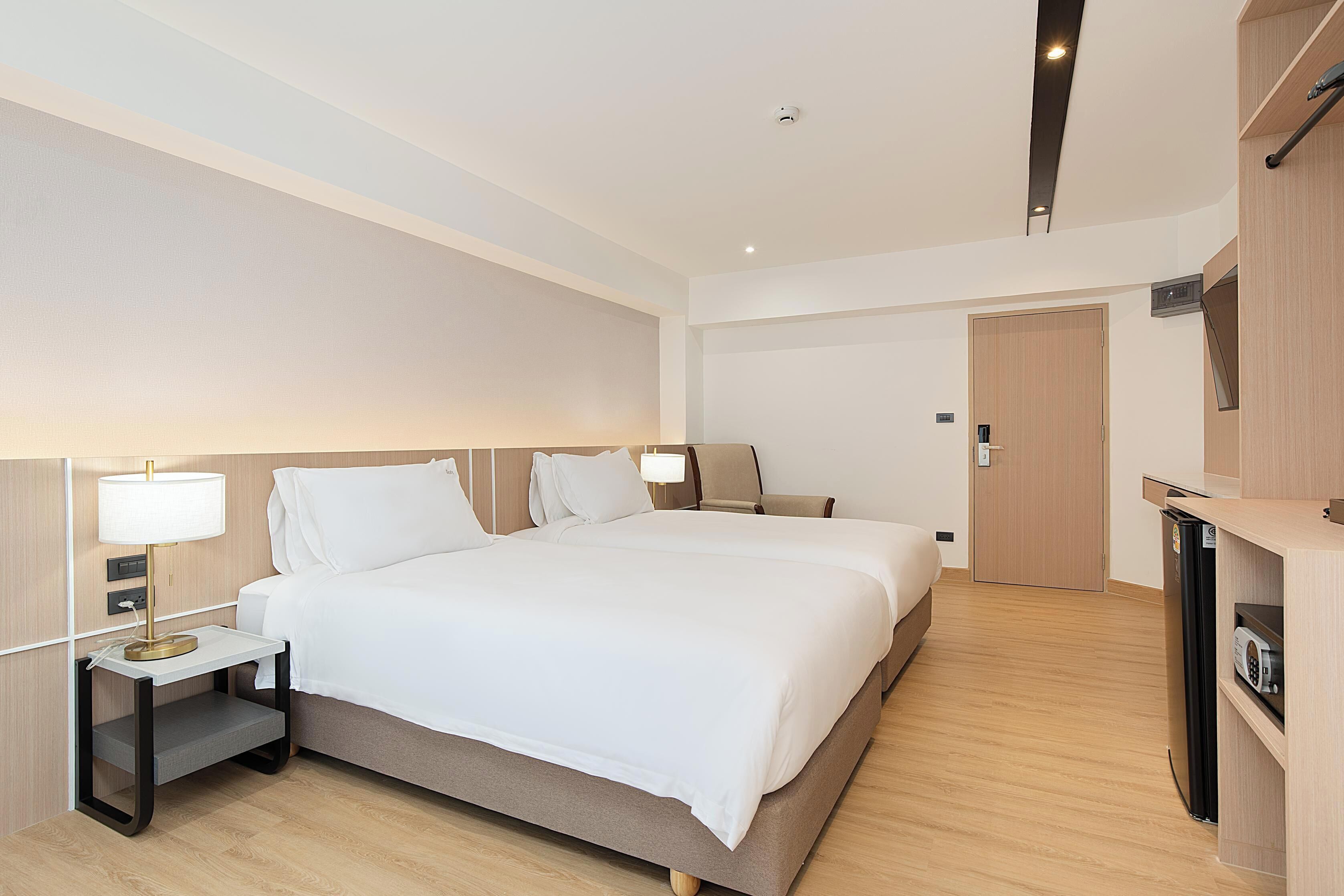 A hotel room with a large bed, bedside tables, a desk, a microwave, and a wardrobe.