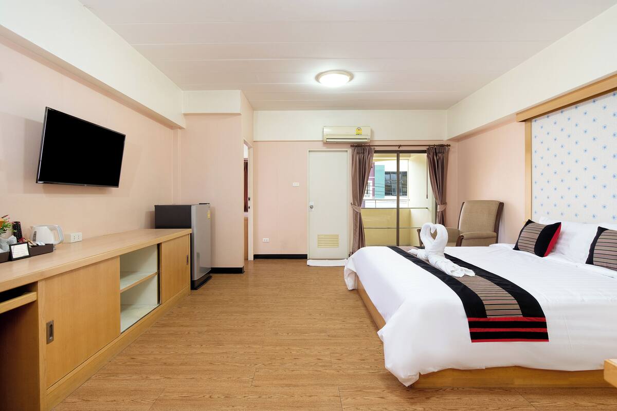 Ein Hotelzimmer mit Bett, Schreibtisch, Fernseher, Klimaanlage und einem Fenster mit Vorhängen.