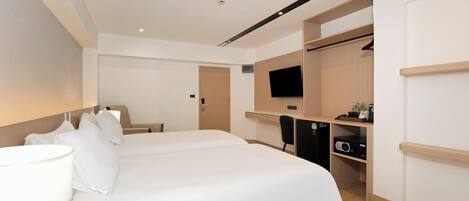 A hotel room with a large bed, a desk, a chair, a TV, and a wardrobe.