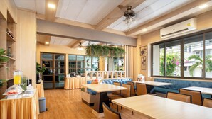 Restaurante com piso de madeira, mesas e cabines, com uma grande janela que oferece vista para o exterior.