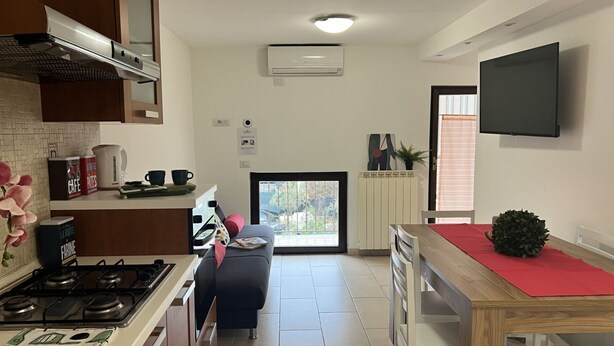 A modern kitchen with a gas stove, a coffee machine, and a dining area with a wooden table and chairs.