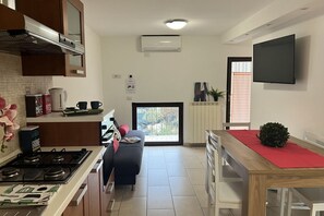 Uma cozinha moderna com fogão a gás, máquina de café e sala de jantar com mesa e cadeiras de madeira.