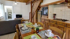 Eine gemütliche Küche mit Holzausbau, einem Esstisch für vier Personen und einer sichtbaren Treppe, die in eine andere Ebene führt.