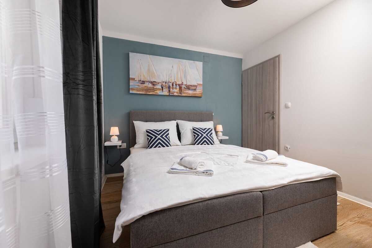 Ein Schlafzimmer mit einem Bett, einem Bild an der Wand, einem Nachttisch und einer Tür.