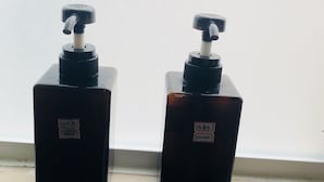 Two brown bottles with pumps, labeled 'soap' and 'shampoo', placed on a windowsill.