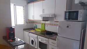 Een kleine keuken met een wasmachine, magnetron en koffiezetapparaat.