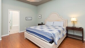 Une chambre à coucher avec un grand lit, une table de chevet, une lampe et une porte.