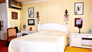 A hotel room with a large bed, a desk with a computer, a chair, and a radiator. - 4 ROOMS IN THE PALACE OF THE HISTORIC CITY (Cannes)