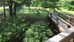 Une terrasse en bois donnant sur un étang, lui-même entouré d’une végétation luxuriante.