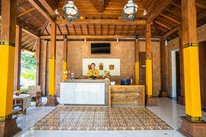 A reception area with a wooden ceiling, a reception desk, and a patterned rug. - djabu Echo Beach Hotel (Canggu)