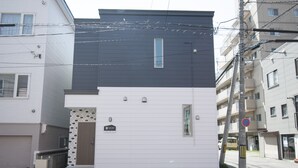 A two-story residential building with a white facade and a dark roof.