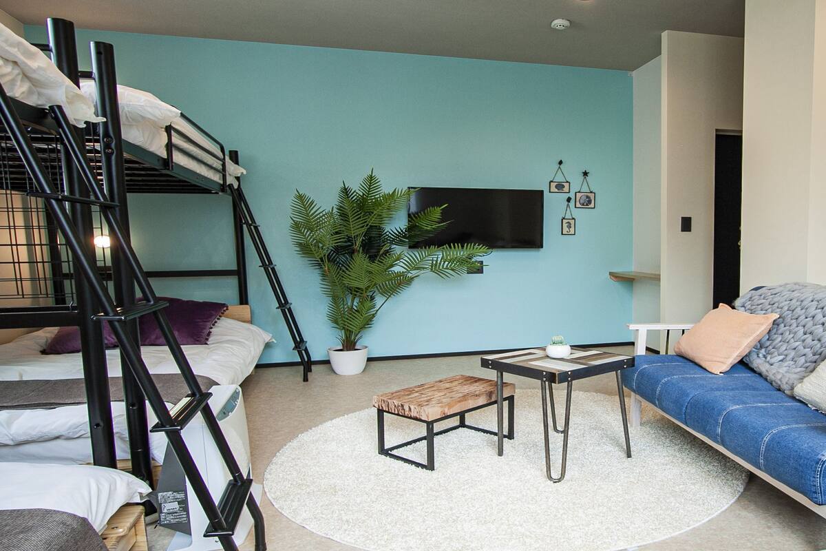 Ein gemütlicher Wohnraum mit Etagenbetten, einer Couch, einem Couchtisch und einem Blumentopf.