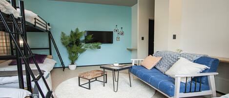 A compact living space with bunk beds, a sofa, a coffee table, and a potted plant.