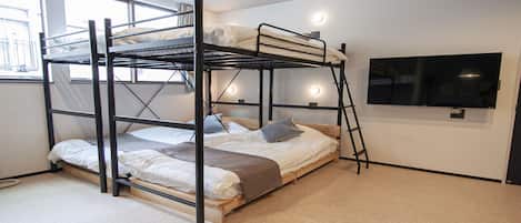 Habitación con literas, un televisor en la pared, una ventana y suelo alfombrado.
