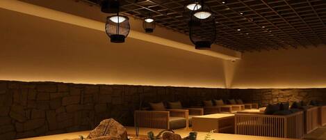 A modern interior with a central rock garden, seating area, and hanging lights.