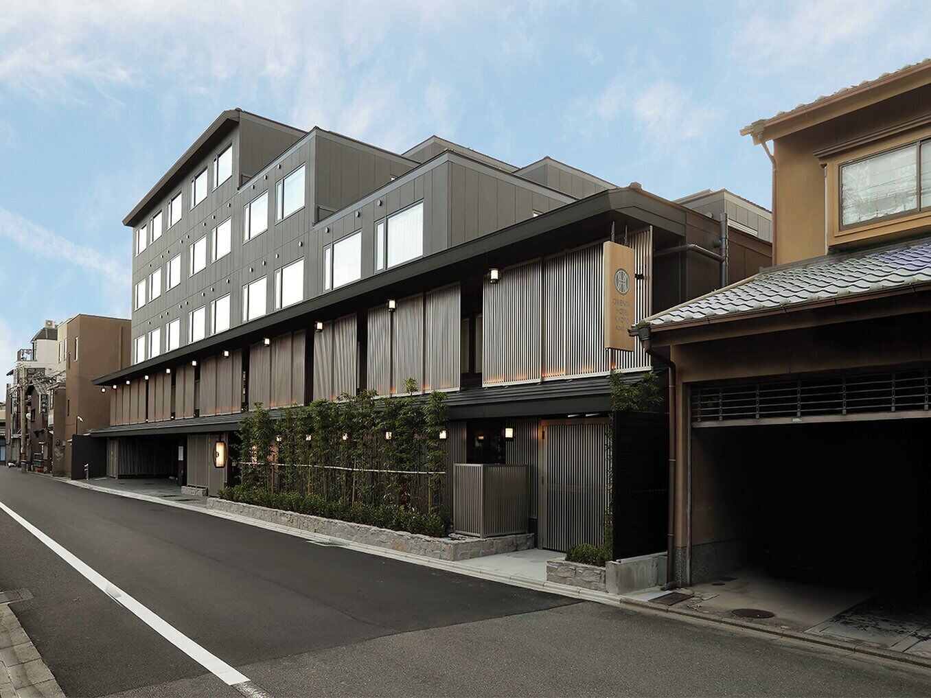 A modern hotel with a flat roof, large windows, and a covered parking area.