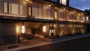 Ein modernes Hotel mit zweistöckiger Bauweise, einem überdachten Eingangsbereich und einem angelegten Garten.