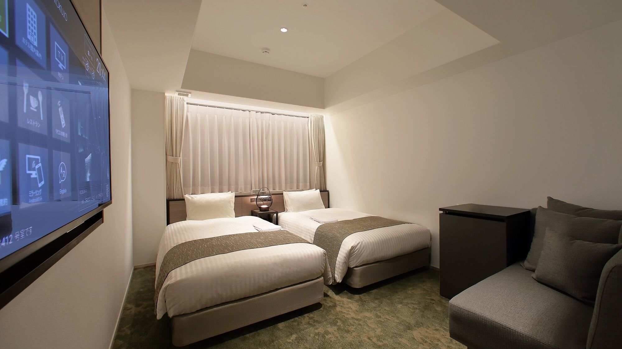 Une chambre d’hôtel avec deux lits, une télévision, un bureau et une chaise.