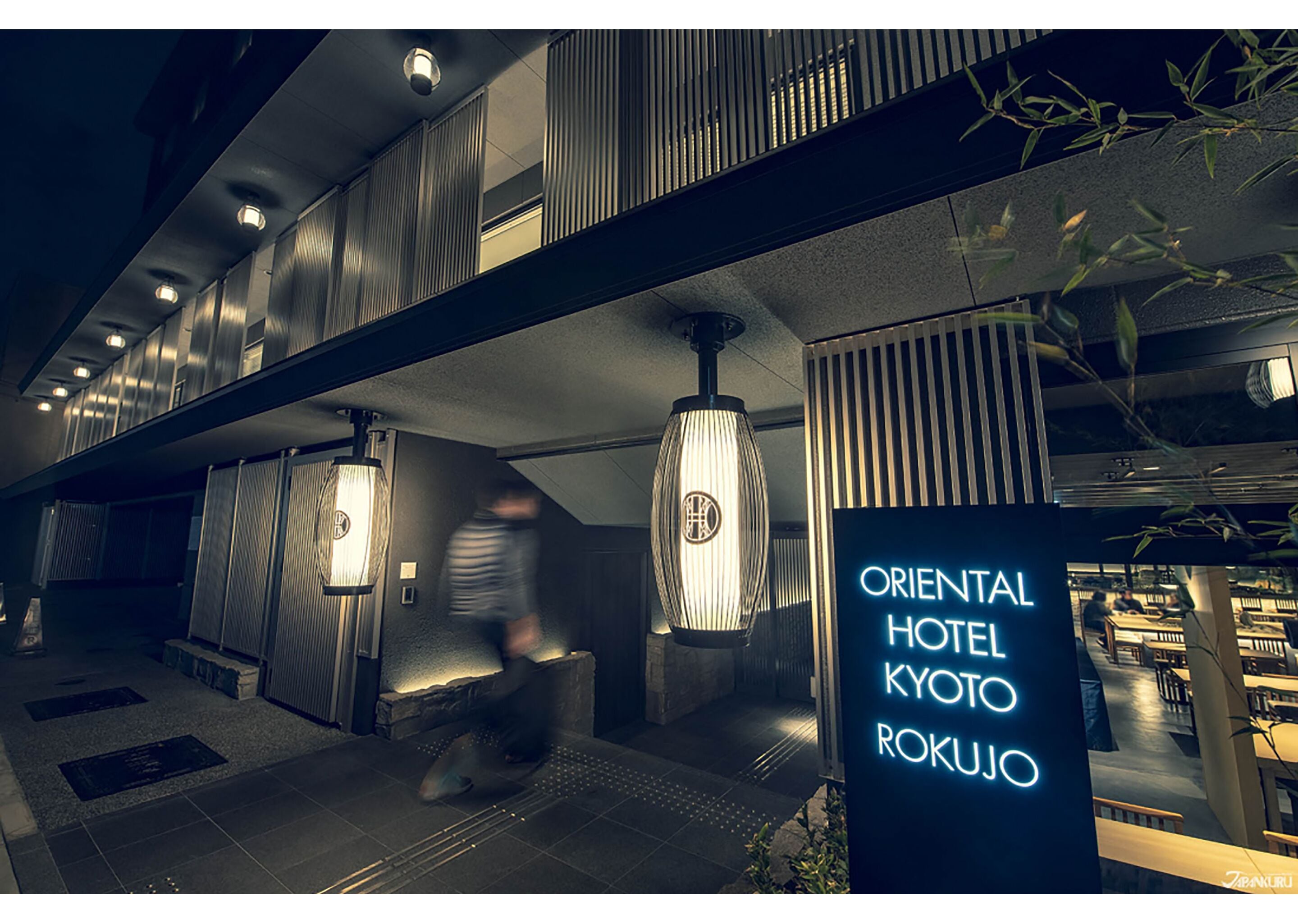 The exterior of Oriental Hotel Kyoto Rokushujo with a modern design, featuring a prominent neon sign, a staircase, and indoor plants.