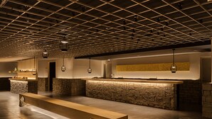 Eine großzügige Lobby mit einer langen Rezeption, Steinverzierungen und hängenden Pendelleuchten.