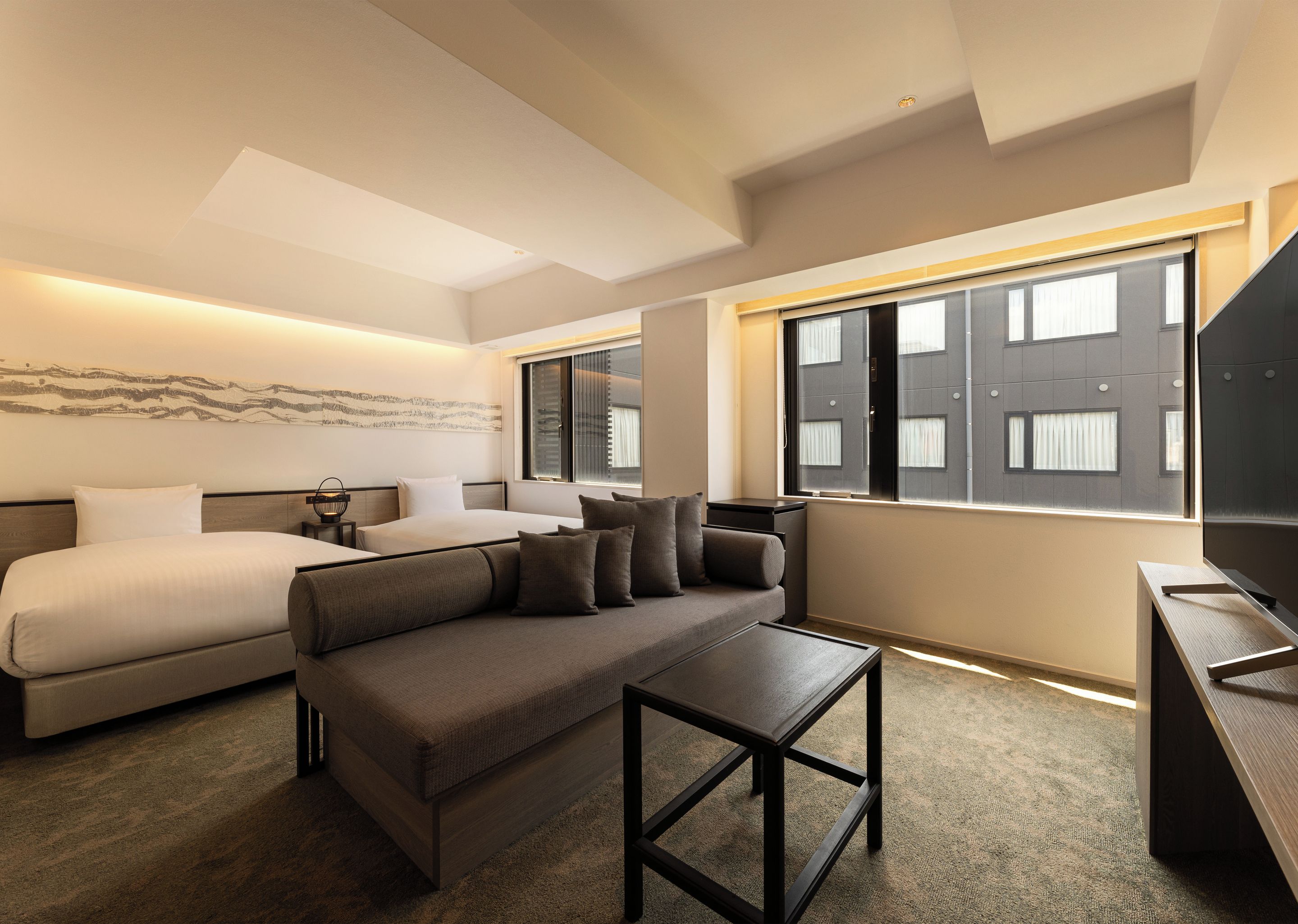A modern hotel room with a bed, sofa, and a small table.