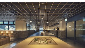 Eine geräumige Lobby mit einer zentralen Sitzecke, Steinwänden und großen Fenstern mit Ausblick.