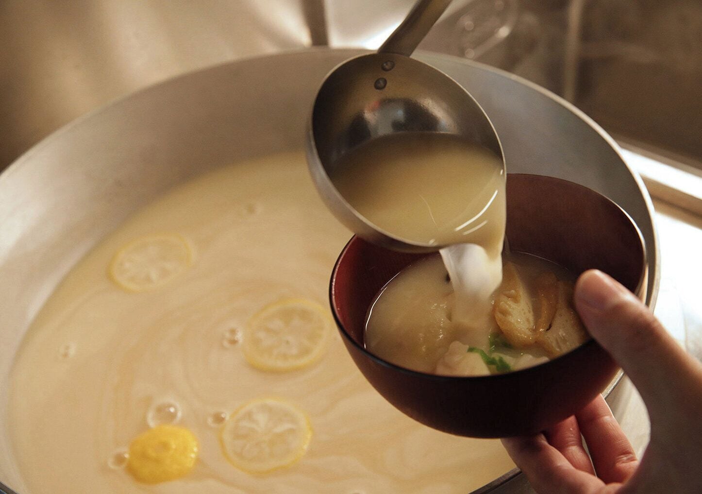 Une personne verse de la soupe d’une grande marmite dans un bol.