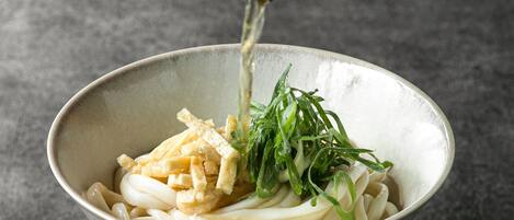 Un tazón de fideos con ingredientes que se añaden.