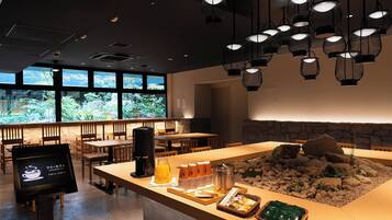 A restaurant with a counter displaying breakfast items, a stone wall, and hanging lights.