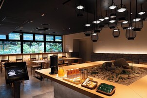 A restaurant with a counter displaying breakfast items, a stone wall, and hanging lights.