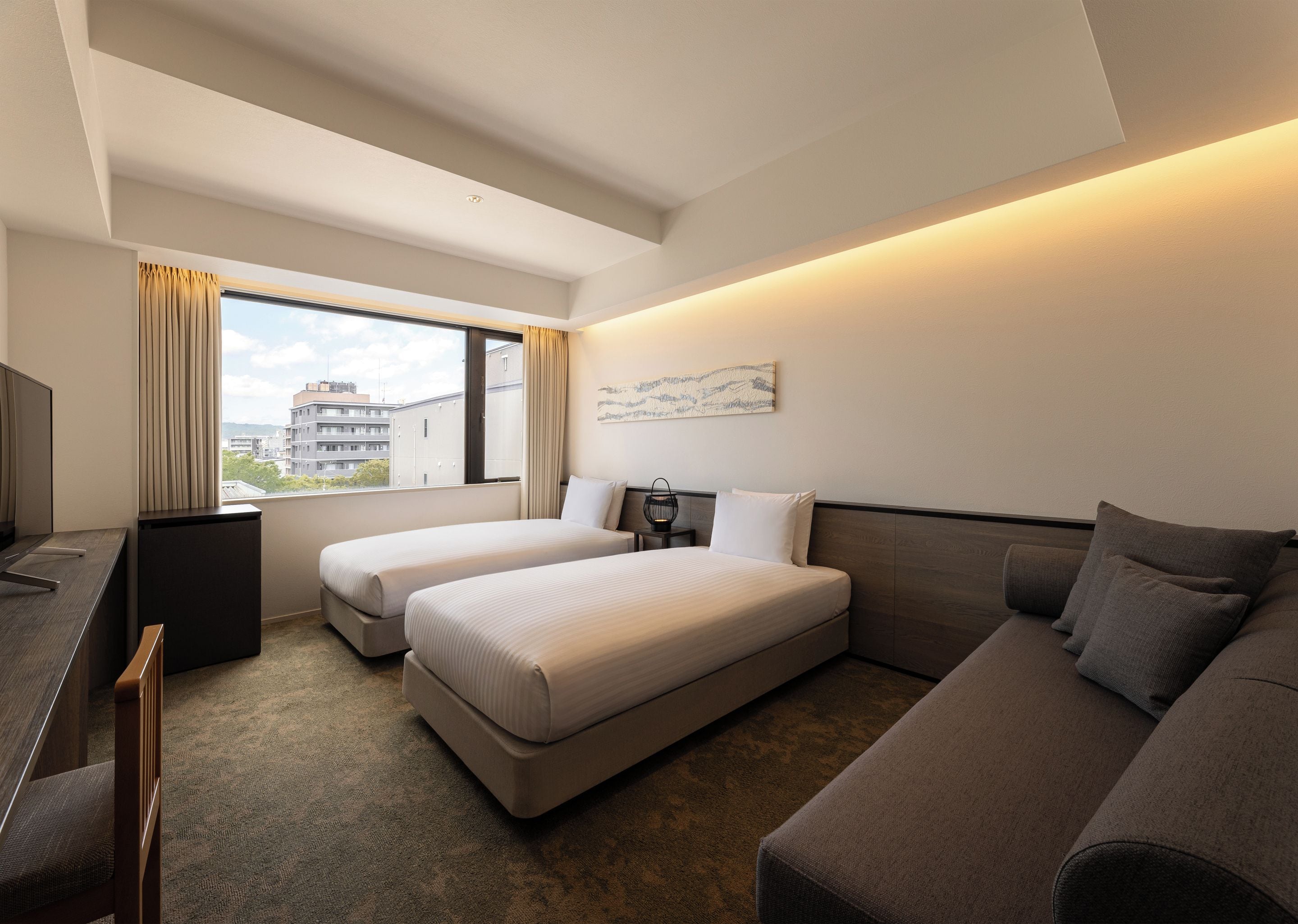 A hotel room with two beds, a sofa, a TV, and a window with curtains.