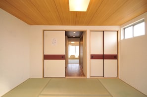 Una habitación japonesa tradicional con suelo de tatami, puertas correderas y techo de madera.