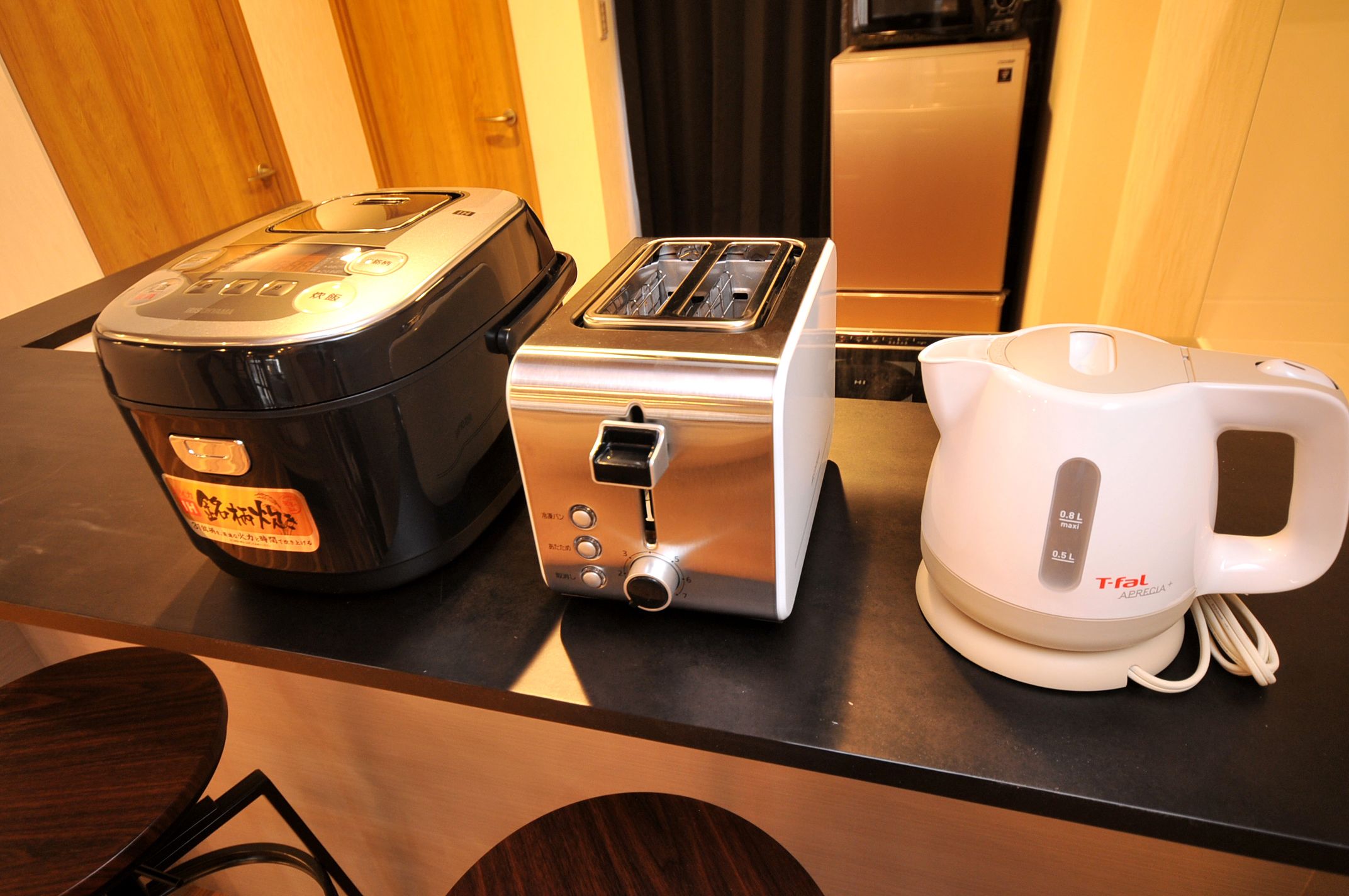 Una encimera de cocina con una cocedora de arroz, un tostador y una tetera eléctrica Tefal.