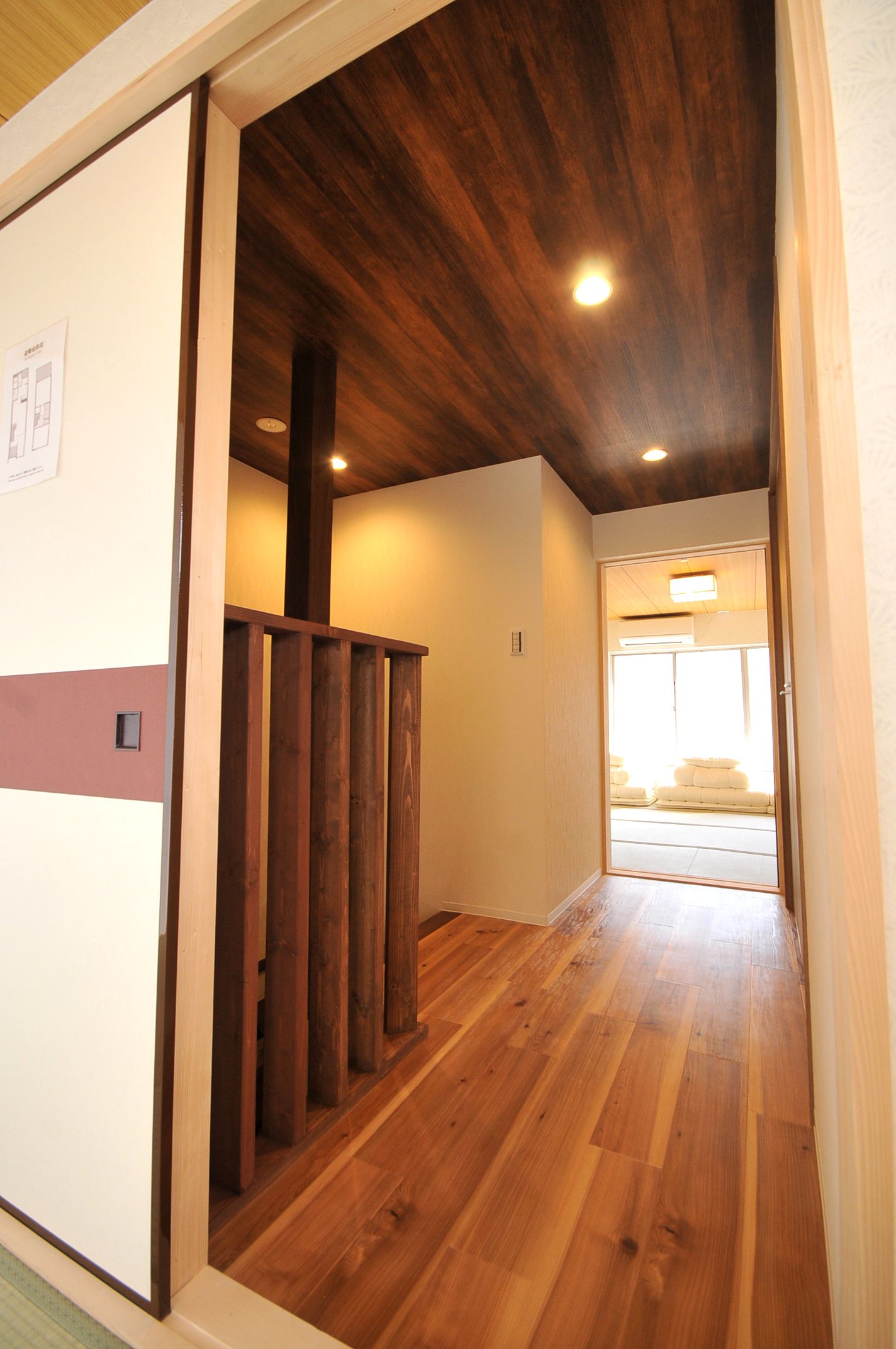 A hallway with wooden flooring and a wooden ceiling.